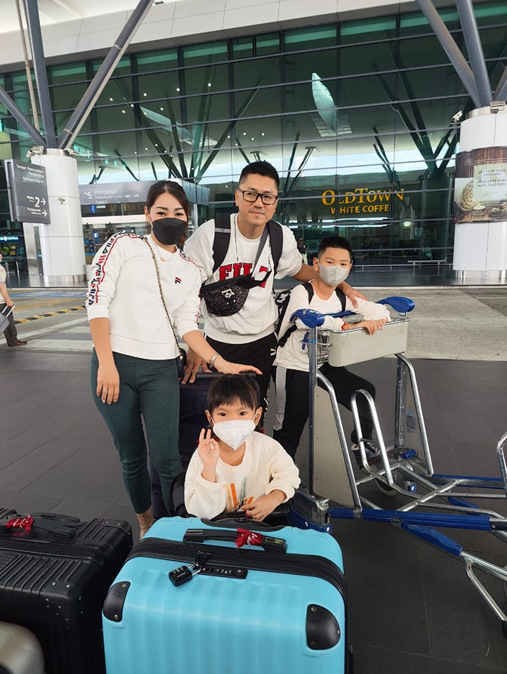 A family with suitcases and a luggage trolley outside the airport terminal