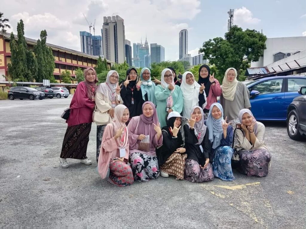 A group of travellers posing together with the Kuala Lumpur skyline behind them