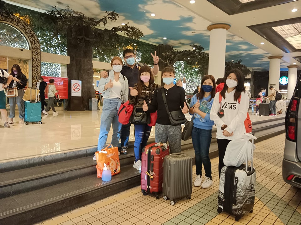 A group of travellers with suitcases in an airport arrivals hall